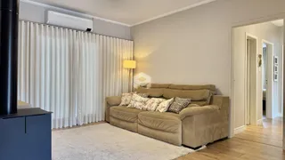 Sala de estar com sofá e cortinas brancas em um imóvel no Brasil.