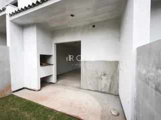 Vista de um corredor interno com paredes brancas e piso de concreto.