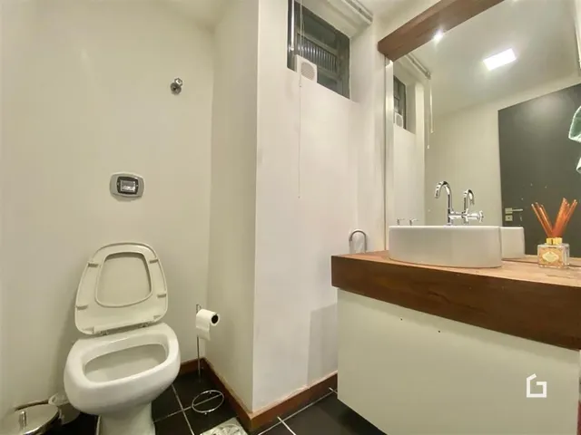 Banheiro interno com vaso sanitário e bancada de madeira.