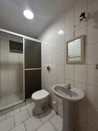 Banheiro com piso e paredes revestidos de cerâmica branca.