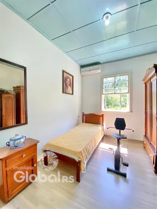 Quarto com cama de madeira e janela em ambiente claro.