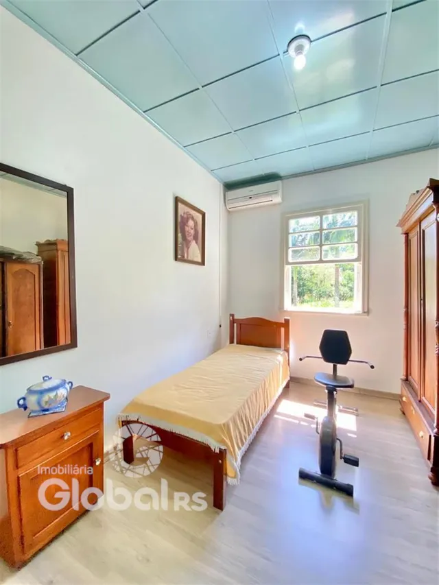 Quarto com cama de madeira e janela em ambiente claro.