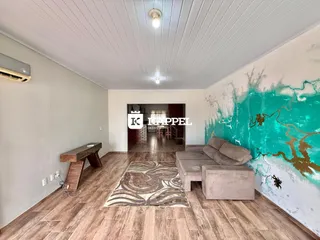 Uma sala de estar com piso de madeira e uma parede decorada com um mural azul turquesa.