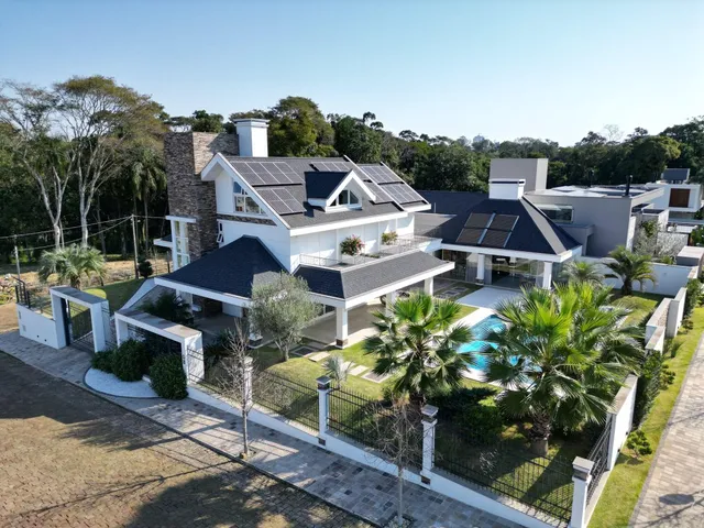 Fachada de uma casa moderna com telhado escuro e painéis solares, exibindo uma piscina no quintal.