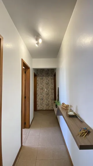 Corredor interno com paredes brancas e piso de cerâmica claro.