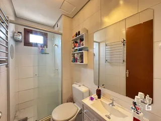 Foto interna de um banheiro com revestimento cerâmico e box de vidro.