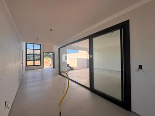 Hall de entrada com piso claro e portas de vidro.