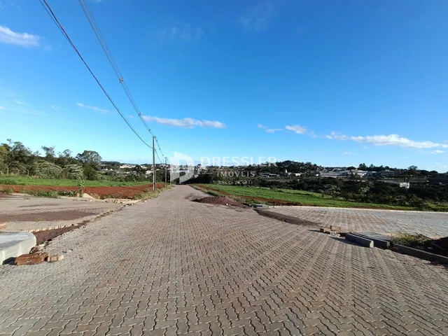 Vista da propriedade com área pavimentada e paisagem ao fundo.