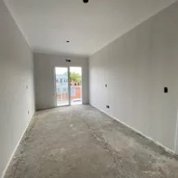 Corredor com paredes brancas e piso de concreto.
