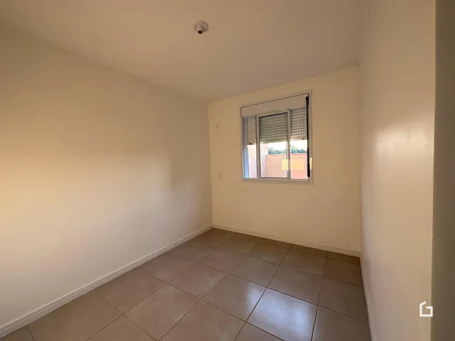 Ambiente interno de uma sala com piso de cerâmica e janela.