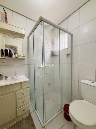 Banheiro com box de vidro e revestimento cerâmico nas paredes.