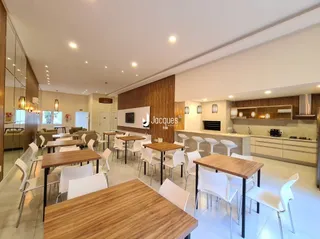 Sala de jantar com mesas de madeira e cadeiras em um ambiente claro.