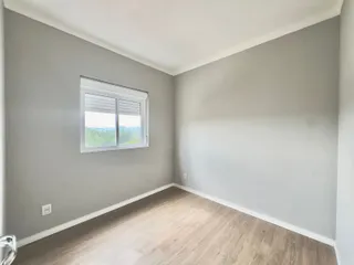 Esta é uma vista interna de uma sala com paredes cinzas e piso de madeira clara.