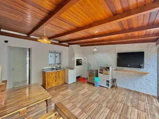 Interior de uma sala de estar com teto de madeira e piso de madeira no Brasil.