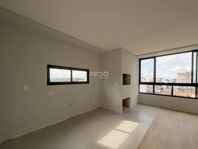 Ambiente interno com paredes brancas e grande janela de vista para a cidade.