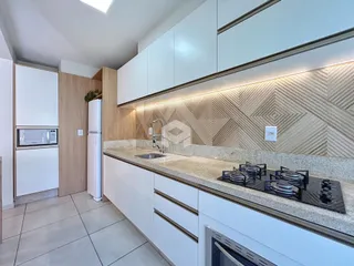 Foto da cozinha moderna com armários brancos e bancada de granito.