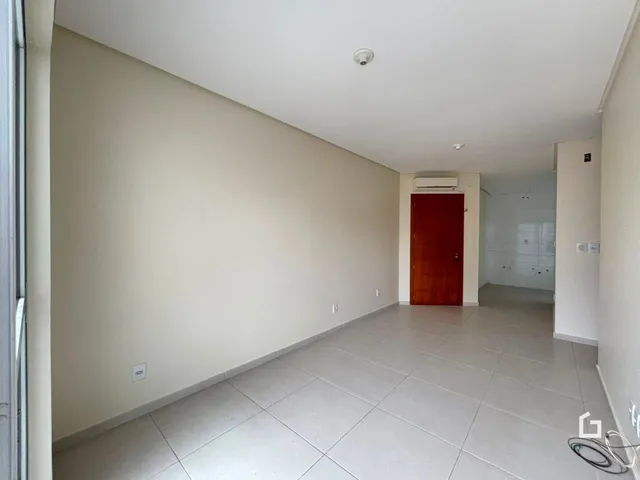 Vista de um corredor interno com paredes brancas e piso de cerâmica clara.