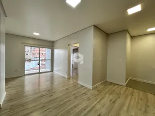 Sala de estar com piso de madeira clara e porta de vidro abrindo para a vista externa.