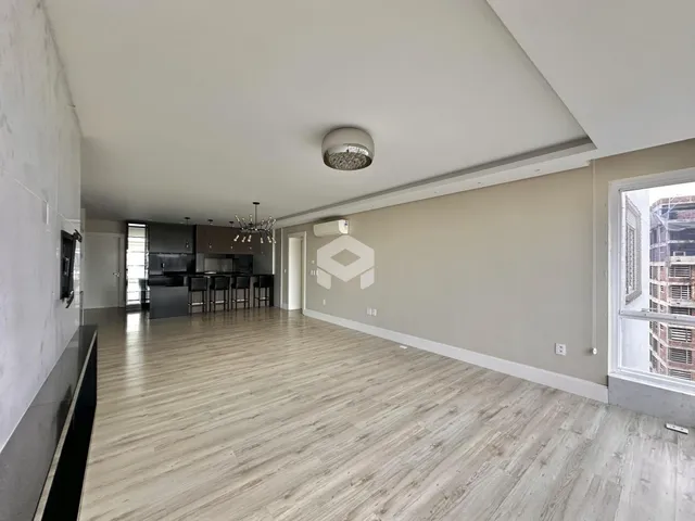 Sala de estar com piso de madeira clara e cozinha integrada.