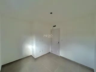 Interior de um ambiente com paredes brancas e piso de cerâmica.