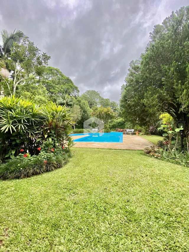 Vista externa de uma piscina e jardim com vegetação exuberante.