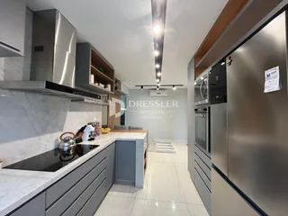 Vista da cozinha moderna com armários e bancadas em mármore claro.