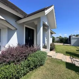 Fachada de uma casa branca com vegetação no jardim.