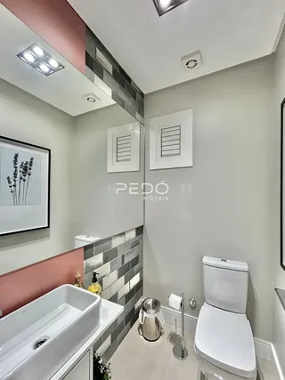 Foto de um banheiro interno com revestimento de azulejos e louças brancas.