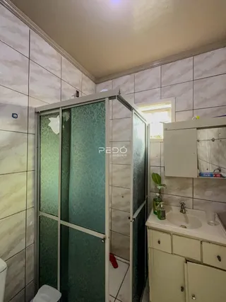 A foto mostra o interior de um banheiro com box de vidro e bancada.