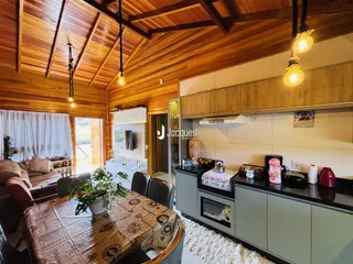 Ambiente de sala de estar e cozinha com teto de madeira no imóvel em Lajeado.