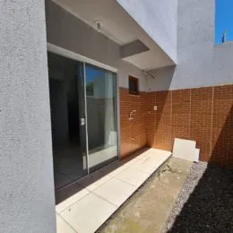 Fachada de um imóvel com parede de tijolos aparentes e porta de vidro.