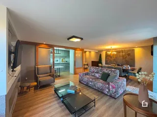 Sala de estar com piso de madeira e sofá estampado em um apartamento em Lajeado.