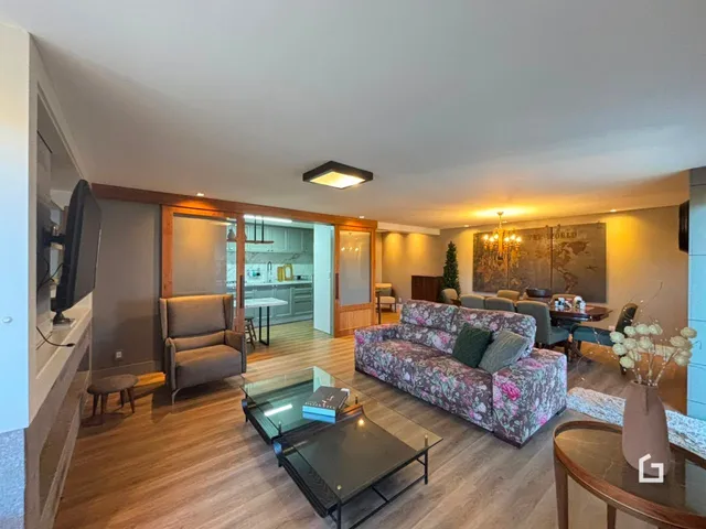 Sala de estar com piso de madeira e sofá estampado em um apartamento em Lajeado.