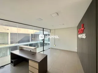 Uma sala ampla com grandes janelas de vidro e um balcão no primeiro plano.