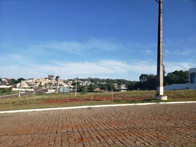Vista externa mostrando uma área pavimentada com vegetação sob um céu azul.