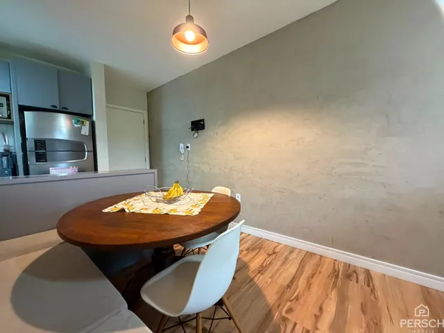 Foto de uma mesa de madeira redonda com cadeiras em um ambiente interno.