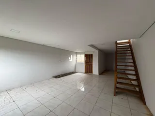 Vista interna de um ambiente com piso de cerâmica e escada de madeira.
