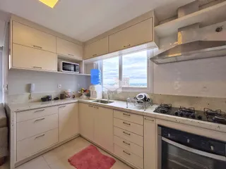Cozinha com armários brancos e bancadas claras em um imóvel.
