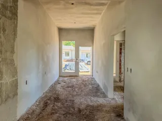 Corredor interno de uma residência com paredes brancas e teto texturizado.