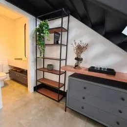 Ambiente interno com estante de metal preta e bancada de madeira.