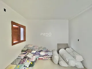Quarto com uma grande quantidade de roupas de cama empilhadas contra a parede.