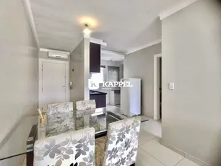 Uma sala de jantar com mesa de vidro e cadeiras decorativas em um ambiente claro.