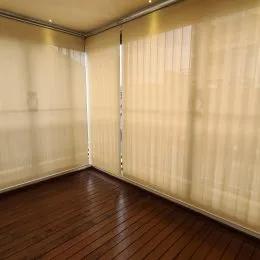 Foto de um ambiente interno com piso de madeira e cortinas claras.