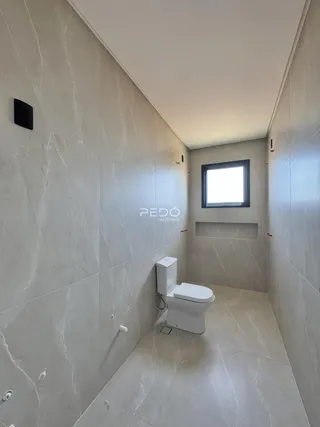 Vista de um corredor de banheiro com piso e paredes em tons de cinza claro.