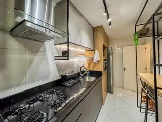 A cozinha moderna apresenta armários e bancadas em tons neutros.