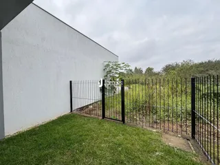 Vista da fachada de uma casa com cerca de ferro e gramado.