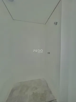 Vista de um canto interno de uma residência com paredes brancas e um degrau no chão.