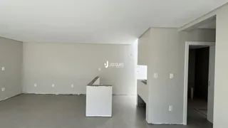 Uma sala vazia com piso de concreto e paredes brancas.