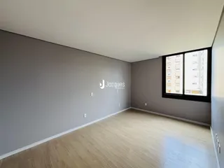 Ambiente interno de uma sala com piso de madeira e paredes cinzas.
