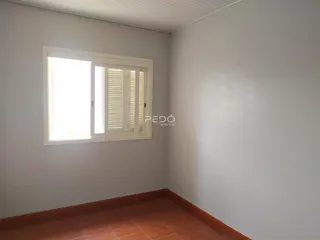 Vista interna de um cômodo com janela e piso de madeira.